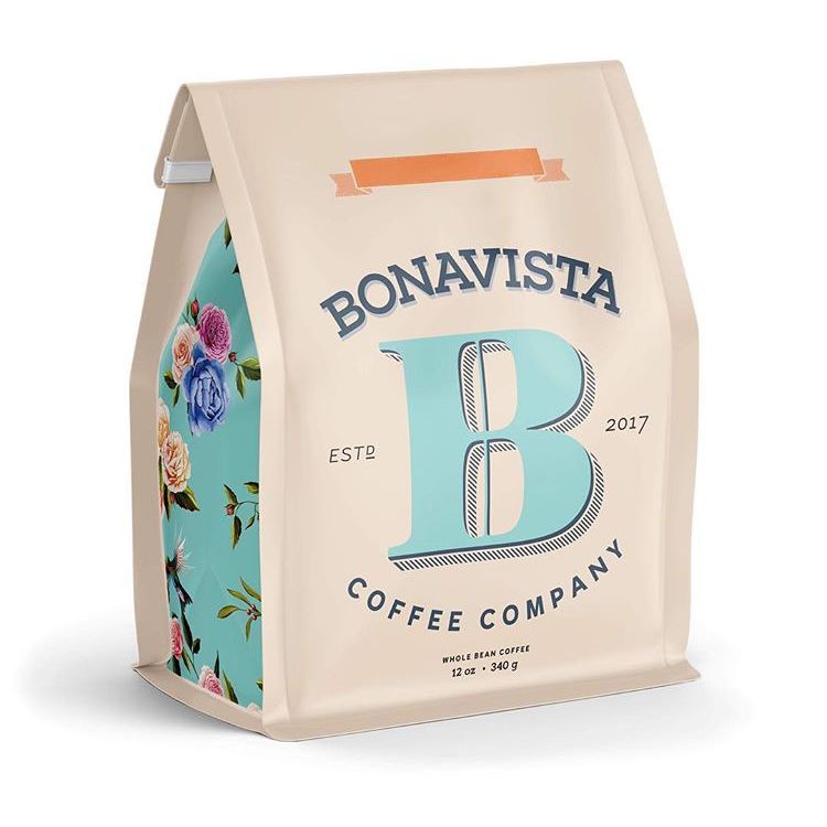 A pouch of coffee beans on a white background. The cream-coloured pouch reads Bonavista Coffee Company with a large decorative letter B in the middle. On the sides of the pouch is a light teal pattern with pink and purple roses.